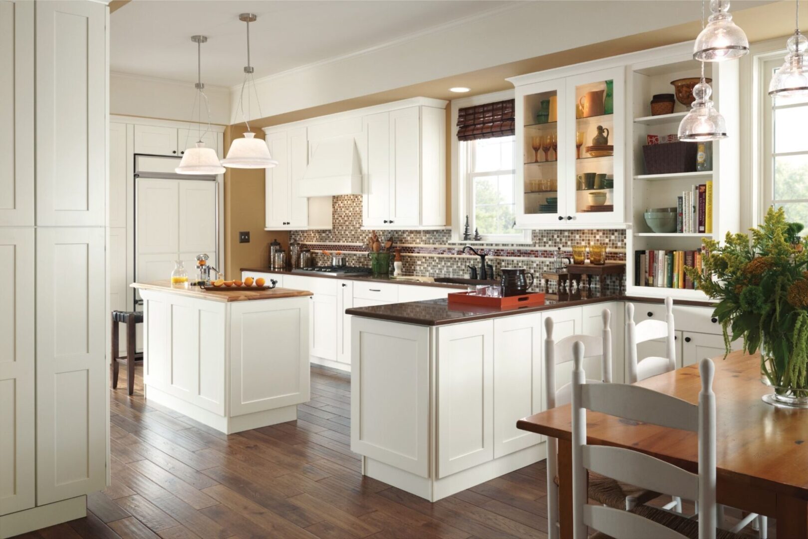 A kitchen with white cabinets and wood floors.