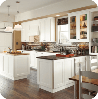 A kitchen with white cabinets and wood floors.